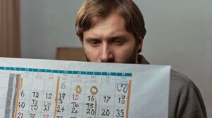 Homem jovem olhando o calendário com expressão compenetrada